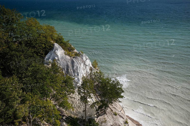 White chalk cliffs at Hundevængsfald with milky water from chalk sediment by the stormy Baltic Sea under a blue sky. Møns Klint, Sjælland, Denmark