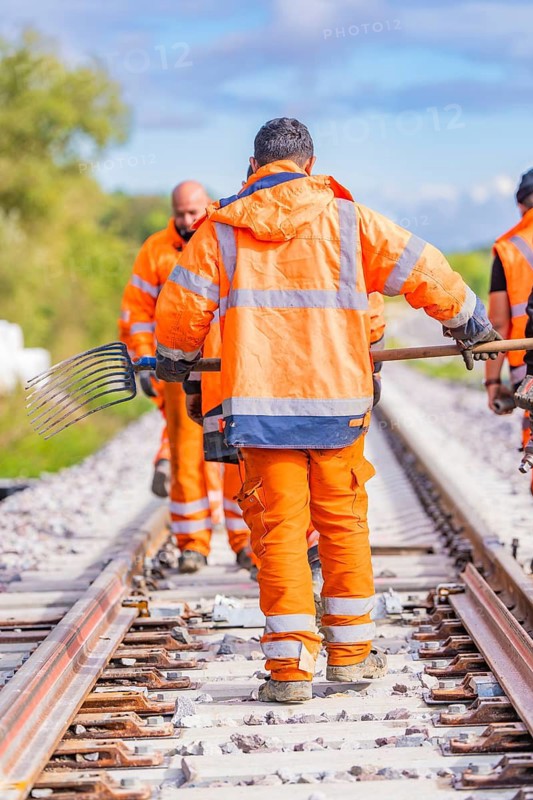 Group of construction workers on the railway tracks in orange work clothes, welding rails, track construction Hermann Hessebahn, Calw, Black Forest, Germany