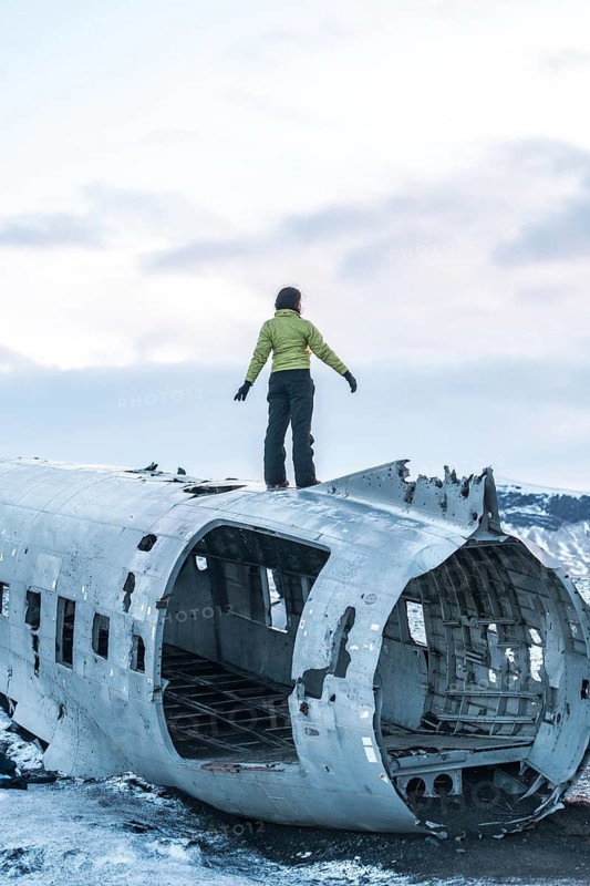 Woman on top of Solheimasandur plane with arms open in meditation in Iceland