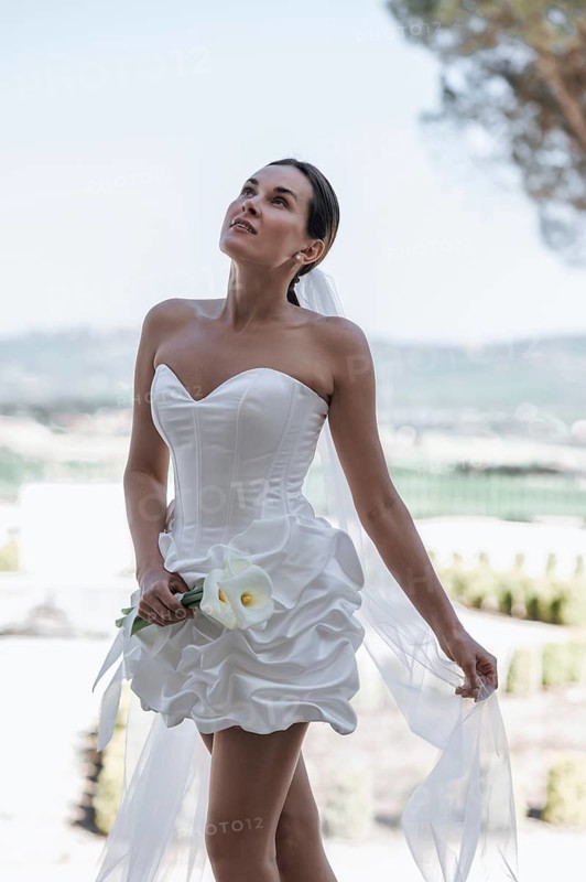 A stunning bride in a strapless gown stands elegantly in the garden of an ancient villa in Treia, Macerata. The scenic backdrop enhances the beauty of Italy's countryside charm