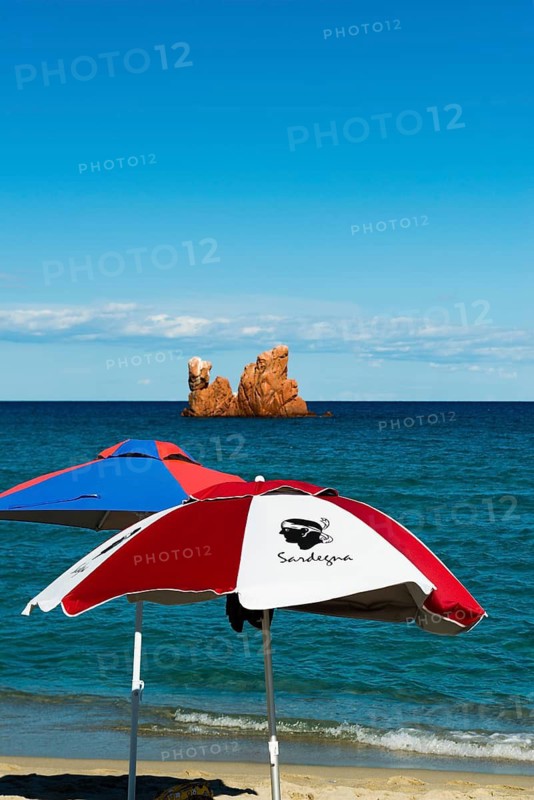 Sunshades on the beach and red rocks, Spiaggia di Cea, Tortoli, Sardinia, Italy