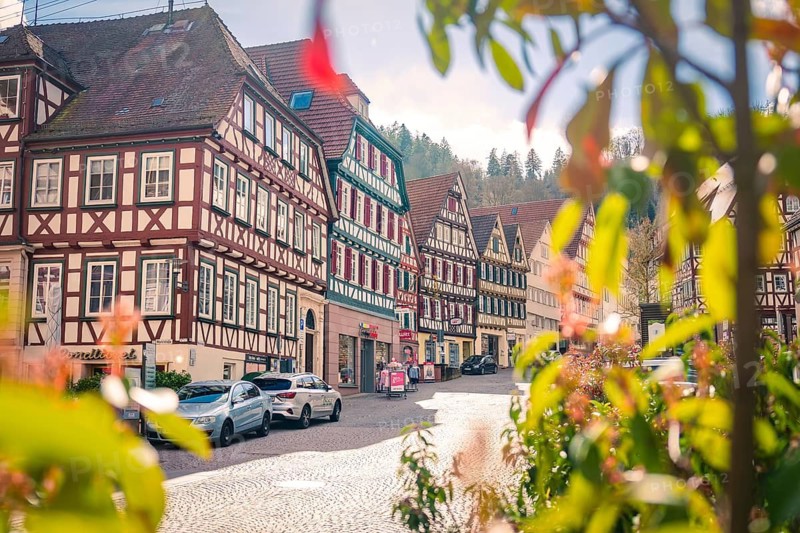 Row of half-timbered houses and parked cars along a cobblestone road, Calw, Black Forest, Germany