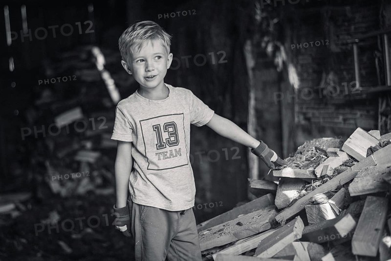 Little boy working in a shed with wood