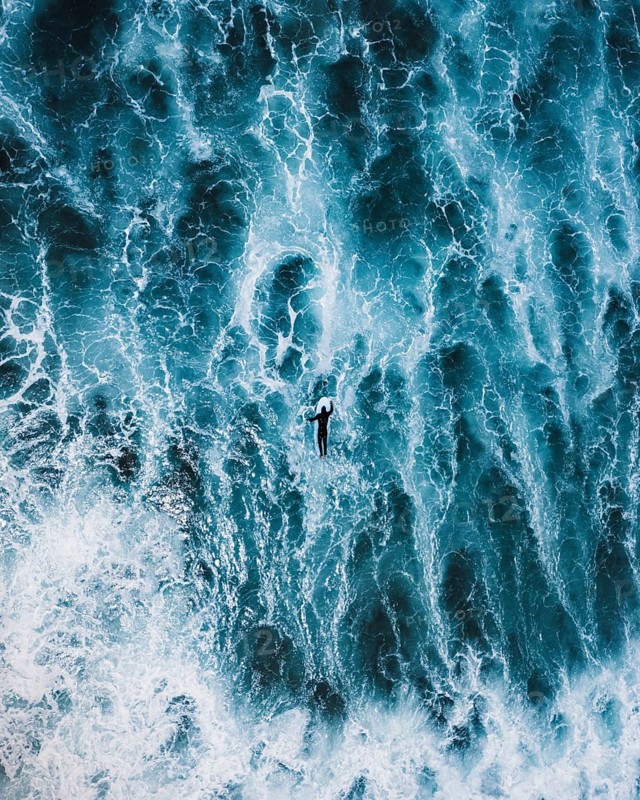 Aerial shot of a surfer navigating the vibrant blue waves in Portugal, capturing the essence of adventure and the dynamic beauty of the ocean in a surfing session