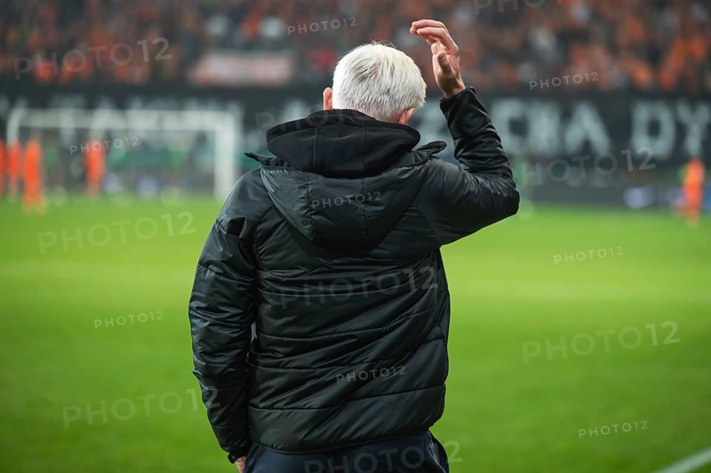 Head coach's back and soccer match at the stadium in the background.