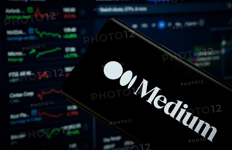 Dhaka, Bangladesh- 17 March 2025: medium logo is displayed on a smartphone screen, with a stock graph webpage visible on a computer screen in the background