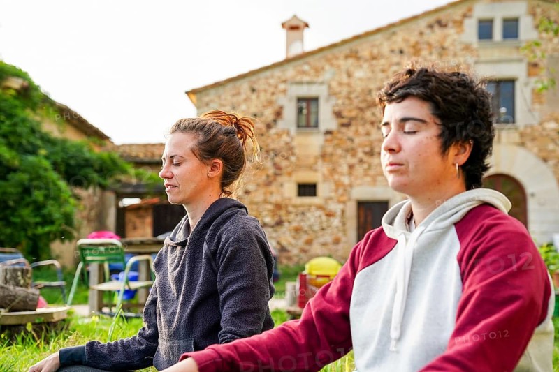 A lesbian couple meditates peacefully in the middle of nature Surrounded by greenery, they find tranquility and connection, embracing love on a quiet camping trip