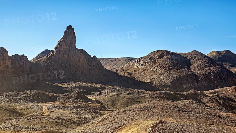 High rock formations in a barren desert landscape under a clear blue sky, The landscape of the Ahaggar Mountains in the Sahara in Algeria