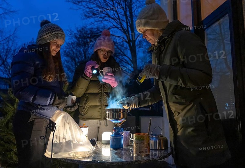 Symbolic picture blackout, extensive, prolonged power failure, in private surroundings, without electricity, heating, water, cooking, heating food and water with a gas-powered camping stove, on the balcony