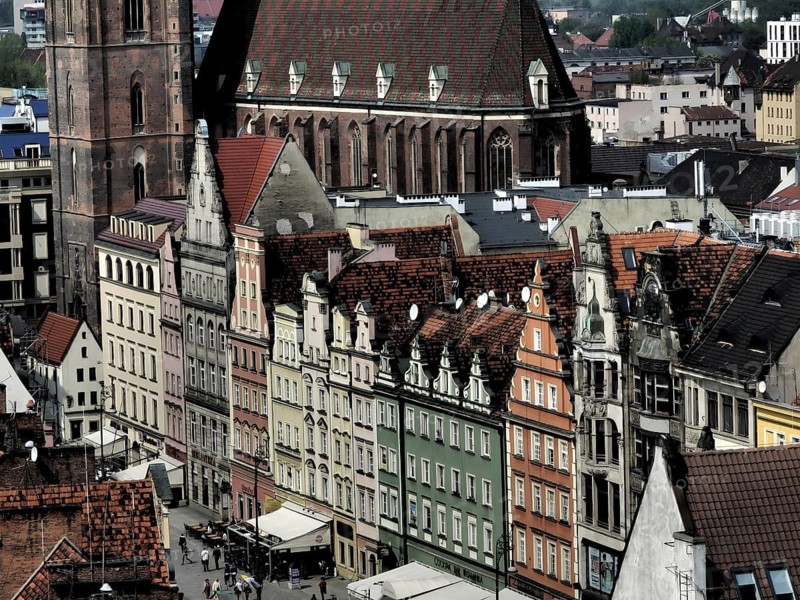 View of the old town of Wroclaw on a series of historic houses with colorful facades and a tall church tower in the background, Wroclaw, Poland