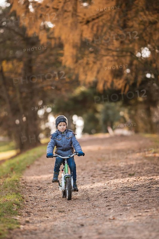 Six years old boy rides bicycle from the hill in the park