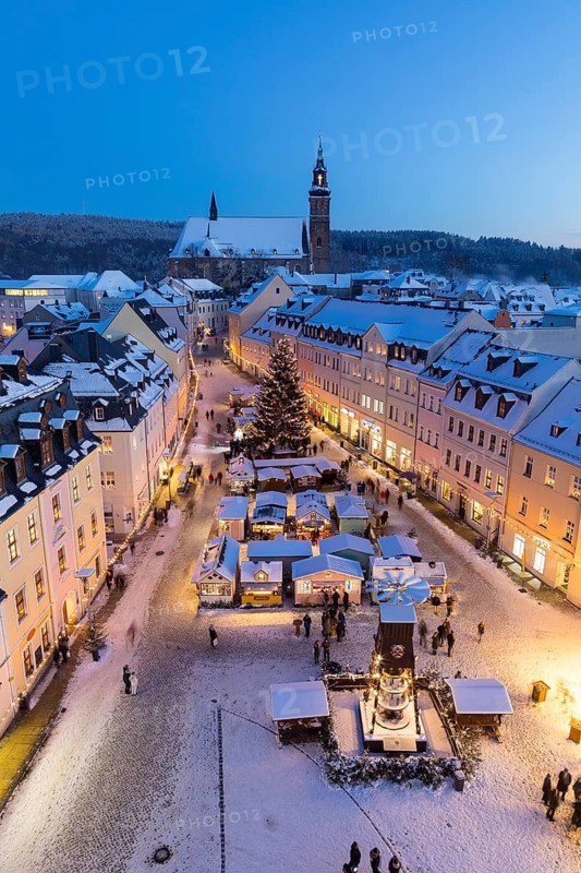 The snow-covered Christmas market with St Wolfgang's church seen from the town hall tower, Schneeberg in the Ore Mountains, Saxony, Germany