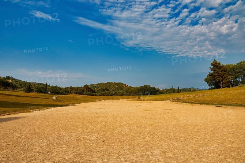 Ancient stadium, wide open field under a vast sky surrounded by light forest, Archaeological Site, Ancient Olympia, Olympia, Peloponnese, Greece
