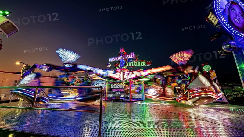 Colourfully illuminated carousel in quick turn at night at a fair, carousel and hustle and bustle of summer winnings in Eisenach