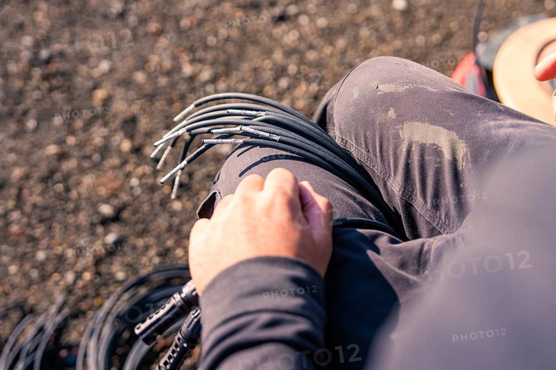 Detailed view of a hand holding cables on a dirty surface while working, PV installation at OBI Baumarkt, Mühlacker, Enzkreis, Germany
