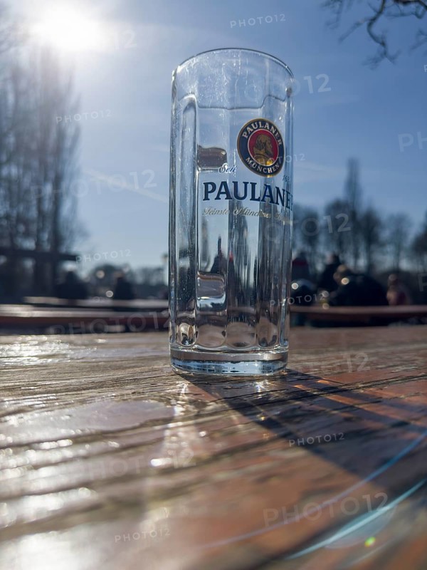Empty Paulaner beer glass on a weathered beer garden table, behind it beer garden visitors, Kleinhesseloher See, Munich, Bavaria, Germany