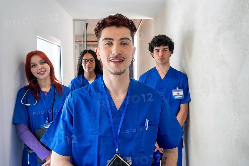 Group of diverse healthcare students in blue scrubs and id badges walking together, preparing for their medical careers, and representing future healthcare professionals