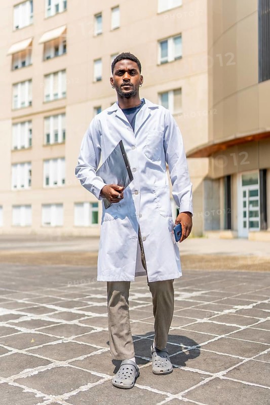Vertical full length portrait of an African doctor with lab coat outside the hospital