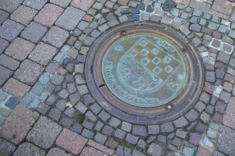 Manhole cover with city coat of arms and wild boar figure, inscription, year, 1368, paving stones, ground, Kirchheimbolanden, Rhineland-Palatinate, Germany