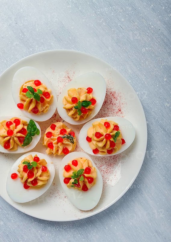 Stuffed eggs, with red caviar, micro greenery, Snack, on a white plate, top view, close-up, no people