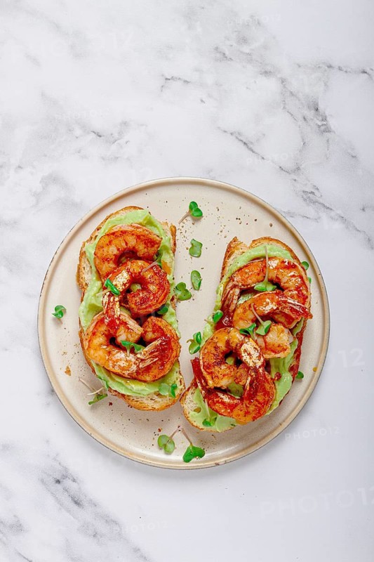 Sandwiches with avocado and caramelized shrimp, micro-greens, breakfast, on a plate, top view, homemade, no people