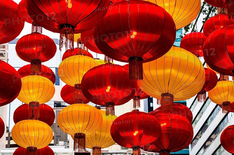A stunning array of red and yellow lanterns brightly illuminated, celebrating Chinese New Year in Hong Kong. The festive lanterns hang densely, creating a warm, glowing ambiance against an urban backdrop