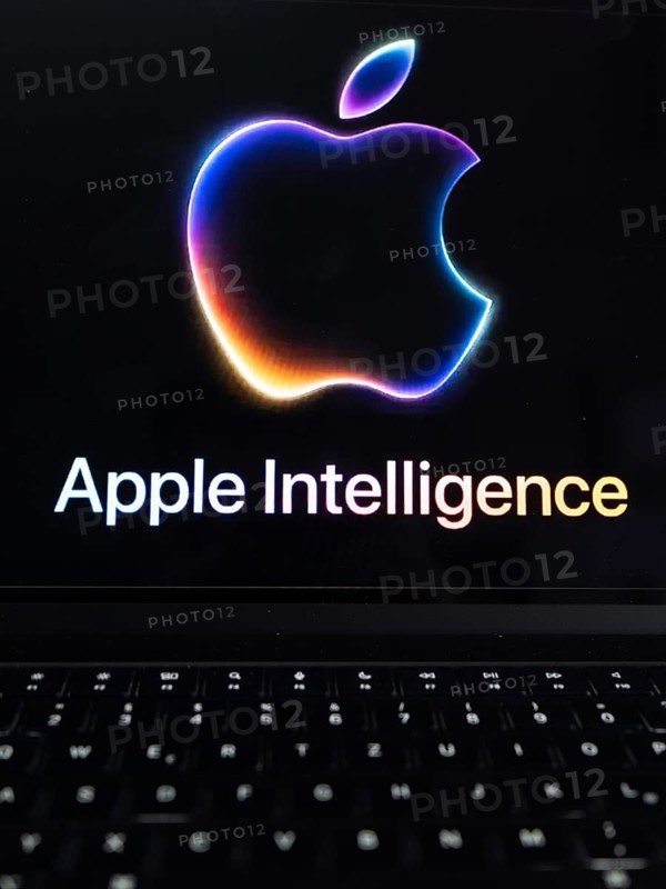 Apple logo in bright neon colours on a Macbook with illuminated keyboard and the text 'Apple Intelligence' underneath, symbolic image of artificial intelligence