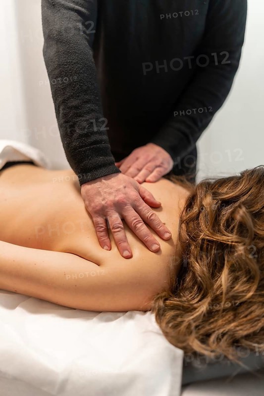 Masseur applying therapeutic pressure and movement on a client's back and shoulders, providing relaxation and relief during a wellness treatment session