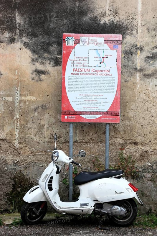 Vespa scooter parked under a sign in Paestum, Campania, Italy