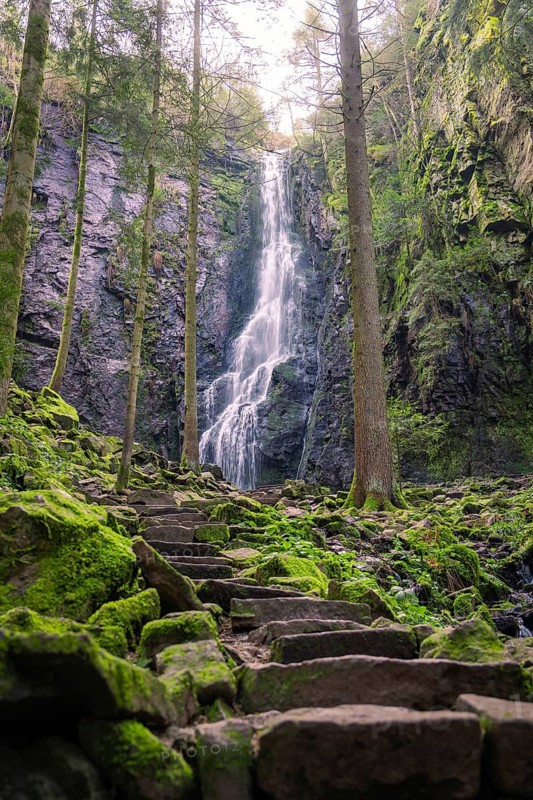 A waterfall in the forest with mossy rocks and a stony path, Burgbach waterfall, Bad Rippoldsau-Schapbach, Black Forest, Germany