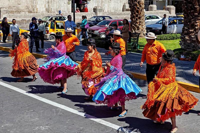 Women in eye-catching clothes perform a lively dance on an urban street, a colorful dance and folklore group in Arequipa in Peru