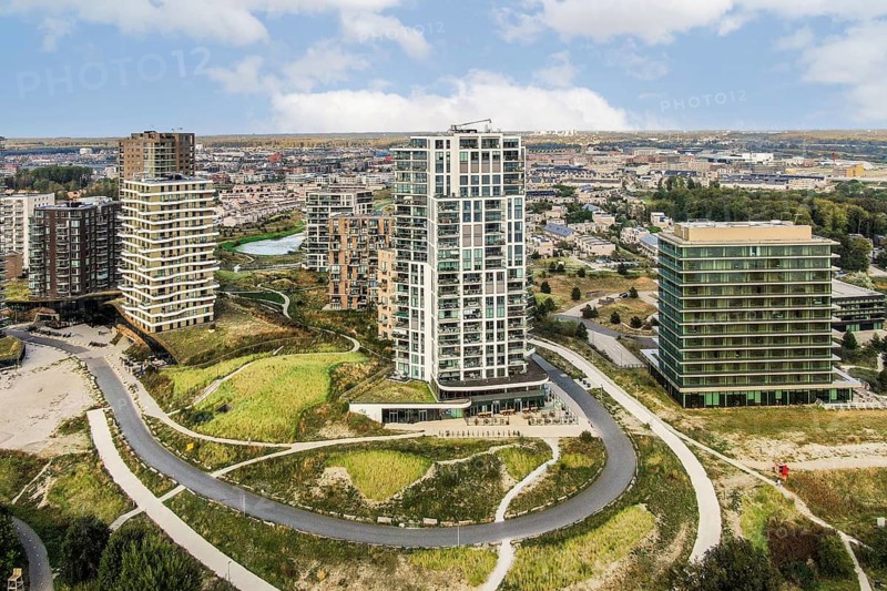 Aerial view of a contemporary urban area featuring high-rise buildings nestled among lush green spaces, illustrating a blend of nature and architecture