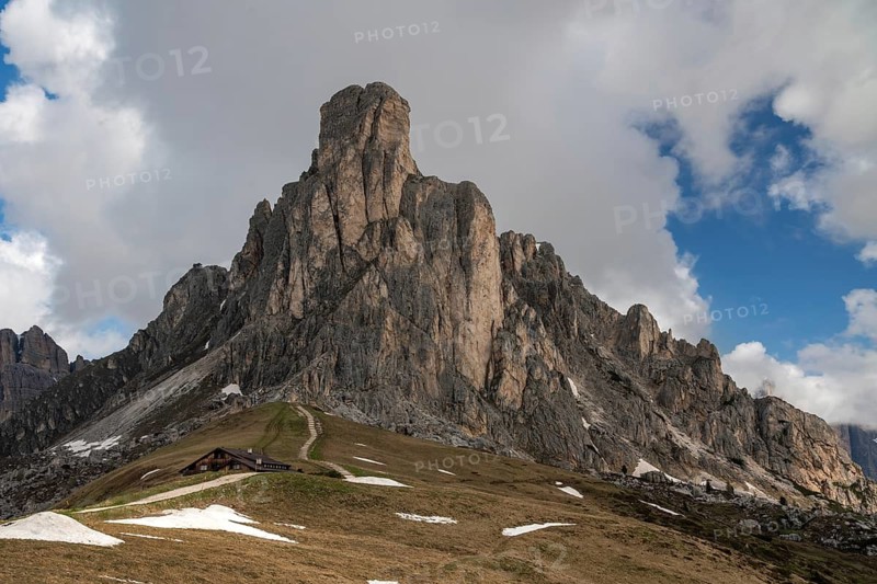 The stunning Passo Giau, located in the Dolomites mountains of Italy, is depicted with dramatic peaks and a cloud-filled sky, showcasing natural beauty and serene landscape