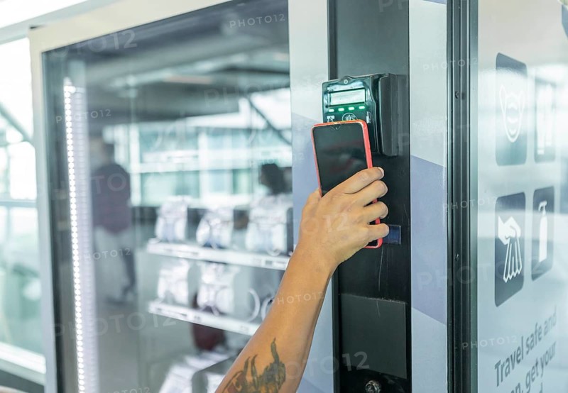 A traveler makes a contactless payment using a mobile phone at a modern airport kiosk The scene emphasizes the convenience and technology in travel settings