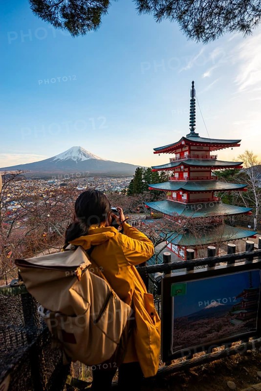 Tourist photographs five-story pagoda of a Shinto shrine, Chureito Pagoda, with views of Fujiyoshida City and Mount Fuji volcano at sunset, Arakura Fuji Sengen Shrine, Arakurayama Sengen Park, Yamanashi Prefecture, Japan