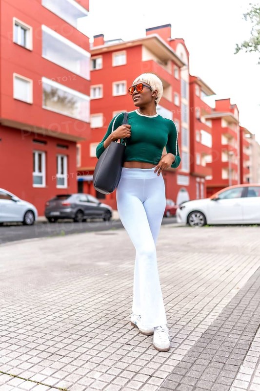 Vertical full length portrait of an urban stylish african woman walking along the city