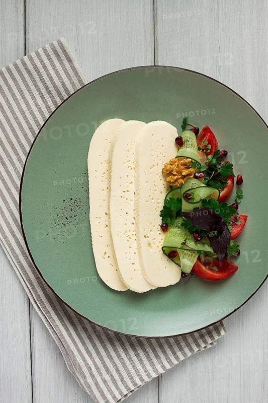 Sliced Imeruli cheese, Georgian cheese, with vegetables, top view, no people