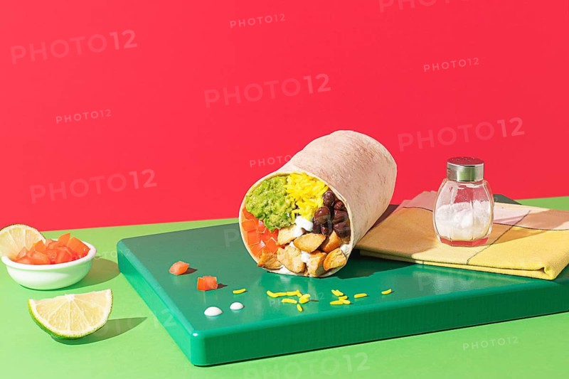 Close-up of a colorful burrito with guacamole, rice and beans, shot in studio with bold lighting and a playful, modern colorful background