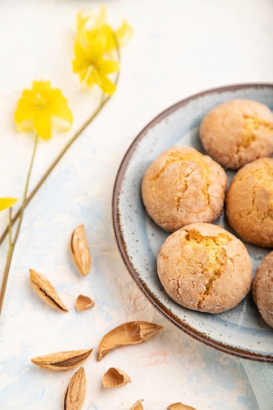 Almond cookies and a cup of coffee on a white concrete background and blue linen textile. Side view, close up, selective focus
