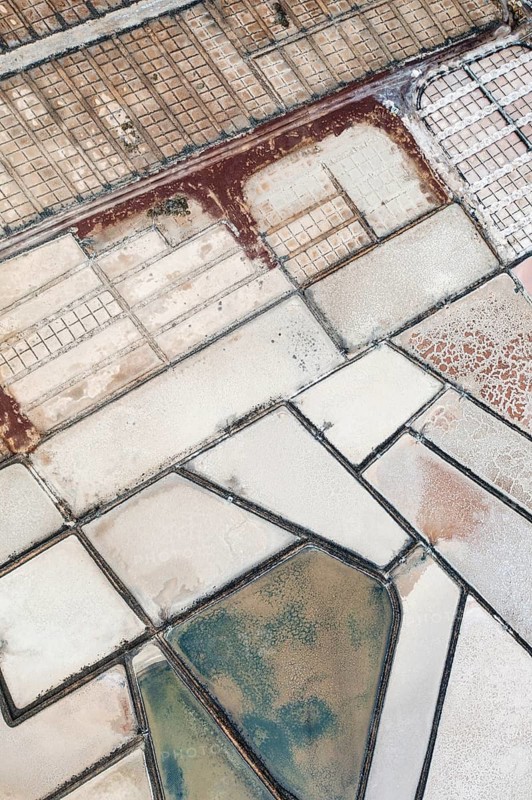 Stunning aerial shot capturing the earthy and vibrant textures of the salt pans at Los Salares de Janubio, Lanzarote, showing the intricacies of salt production
