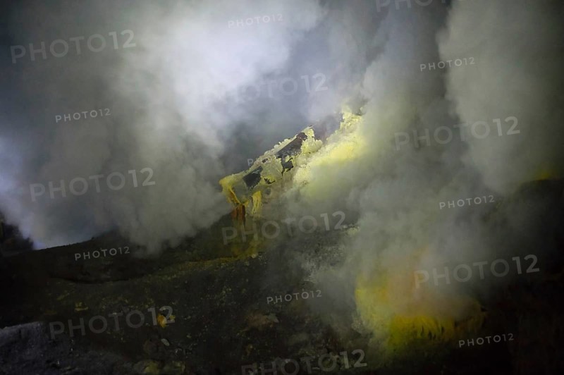 Thick sulfur smoke rises from Ijen's crater vents, with visible yellow mineral deposits formed by volcanic gases