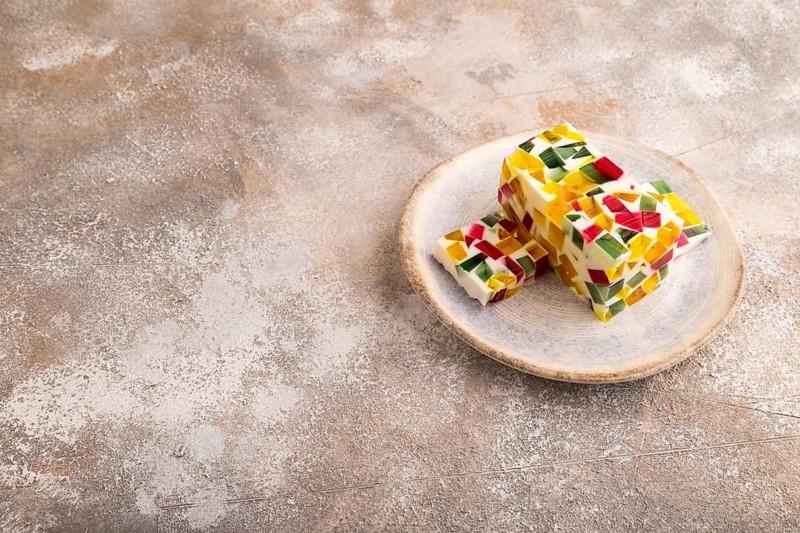 Colored Fruit and milk jelly on brown concrete background, side view, copy space, minimalism