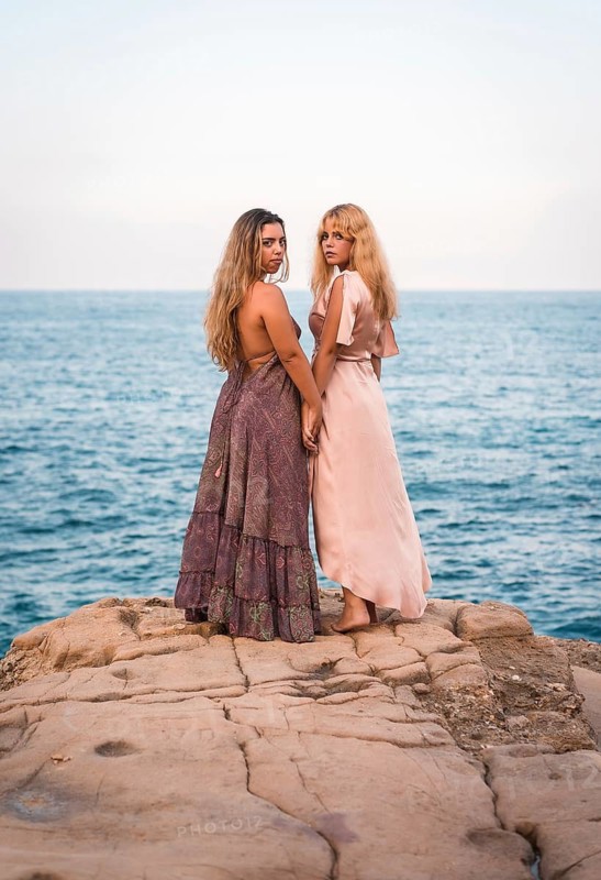 A couple of Caucasian girls in beautiful dresses enjoying the summer, shaking hands in an affectionate way