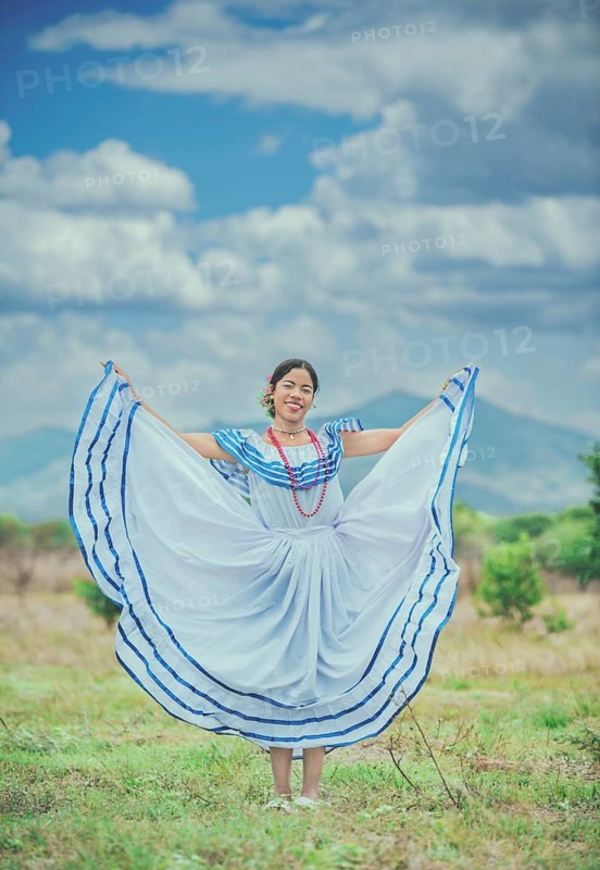 Young Nicaraguan woman in traditional folk costume in a field. Portrait of Nicaraguan girl in traditional folk costume outdoors