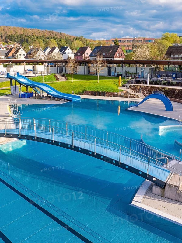 Complex outdoor pool with bridge and slide, surrounded by a picturesque landscape, Calw Stammheim outdoor pool, Calw, Black Forest, Germany