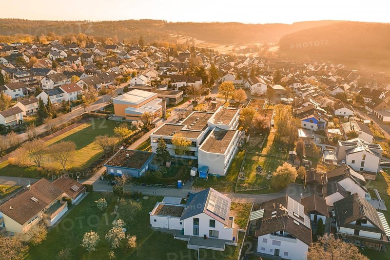 Extensive suburban view with houses and green spaces in warm evening light, Schlehengäuschule, Gechingen, Hecken and Gäu region, Calw district, Germany