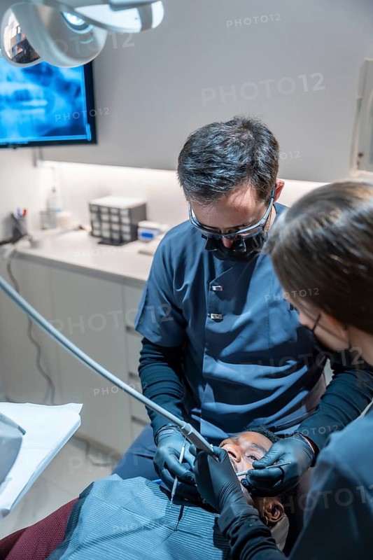 Dentist and dental assistant working together, performing a dental procedure on a patient in a modern dental clinic