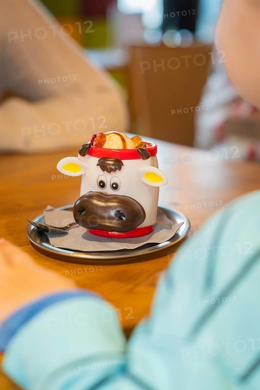 Child enjoying dessert in a funny cow cup with cream and cherries, autumn creations, Cafe Kuh, Deckenpfronn, Black Forest, Germany