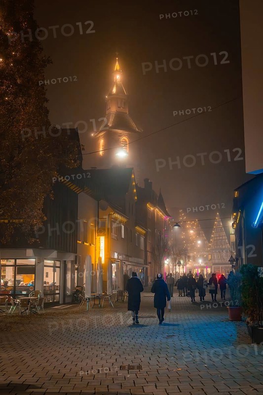 Evening street scene with illuminated church tower, pedestrians and Christmas atmosphere, Christmas market, Nagold, Black Forest, Germany