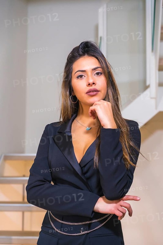 Lifestyle, portrait of brunette Caucasian girl in a black elegant suit posed on the stairs of a hotel, fashion photo